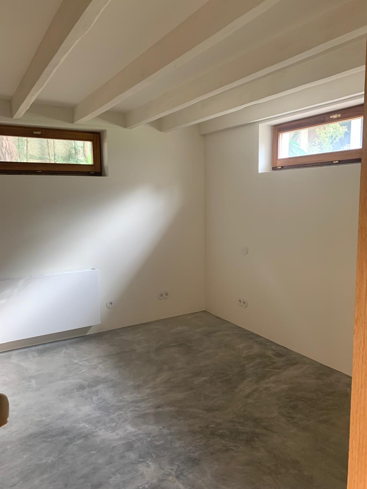 Lower ground room with ribbon windows, beamed ceiling and microcement floor