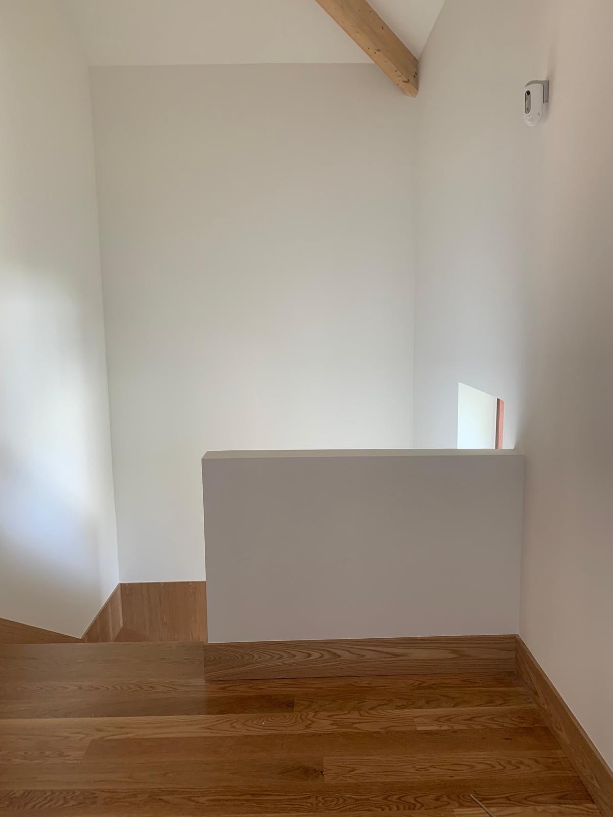 Bright upper landing with exposed pine beam, white parapet and oak floor