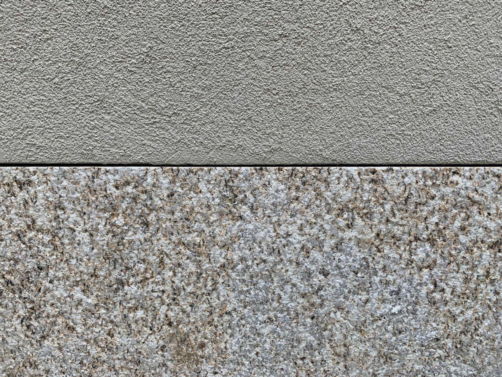 Detail of new render meeting a bush-hammered granite plinth on a Porto facade