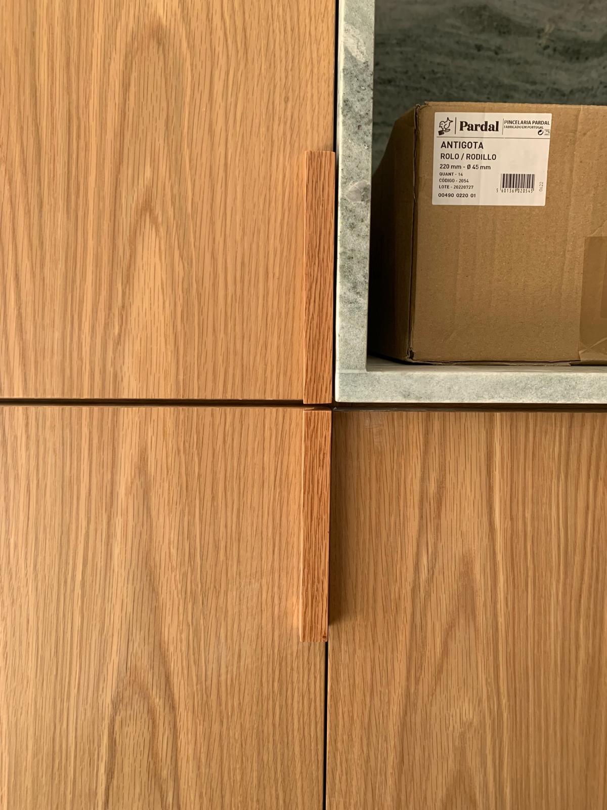 Close-up of oak cabinet fronts with a machined timber pull and stone shelf